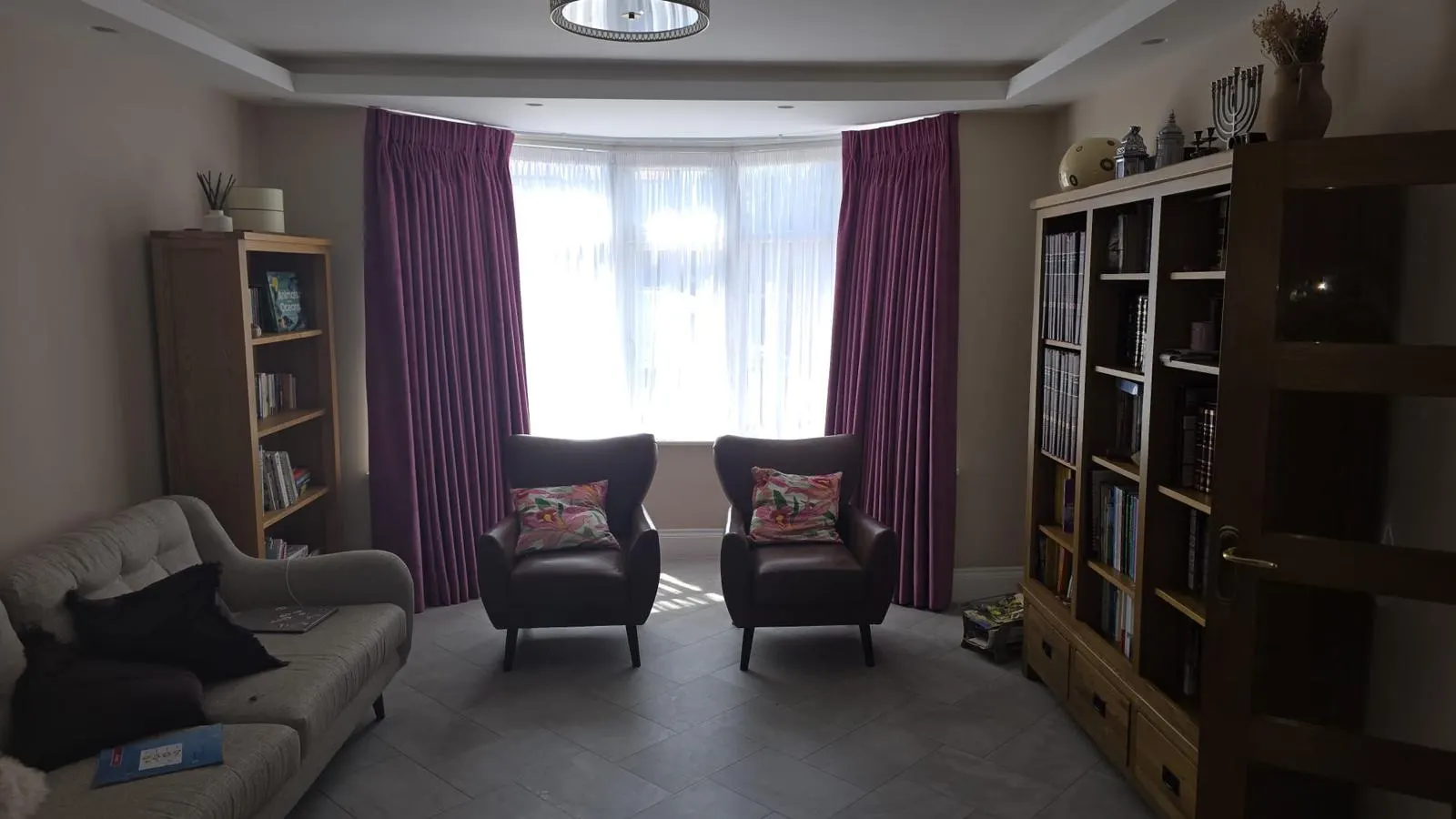Plum pinch-pleat curtains and sheers dressing a wide bay window