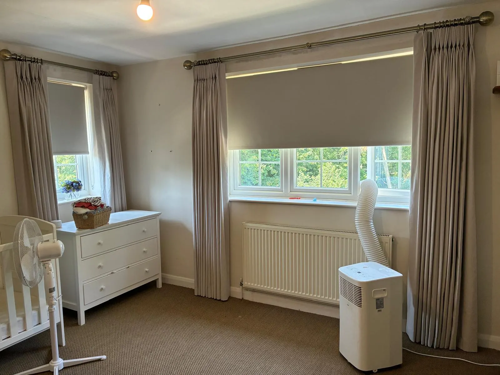 Blackout roller blinds layered with curtains in a nursery
